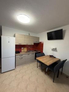 a kitchen with a wooden table and a white refrigerator at Apartman 5 Majba in Zaglavice +5 photos