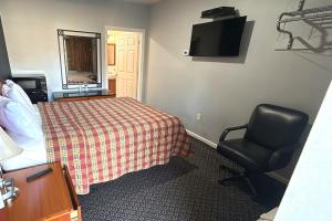 a bedroom with a bed and a chair and a television at At 9 Motel Near Freehold I-195 in Howell +29 photos