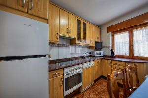 a kitchen with wooden cabinets and a white refrigerator at Casa Rural EL COTARRO DE PESQUERA DE DUERO in Pesquera de Duero