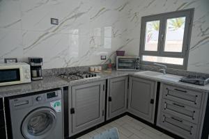 a kitchen with a washing machine and a microwave at BBS Maison in Douz +7 photos