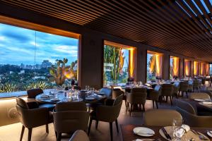 a restaurant with tables and chairs and large windows at Hotel Unique in São Paulo