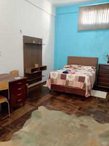 a bedroom with a bed and a dresser and a desk at Hostel Uziel in Timbó
