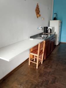 a kitchen with a sink and a counter with a wooden stool at Hostel Uziel in Timbó +7 photos