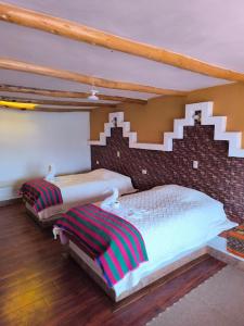 a bedroom with two beds and a brick wall at Puma Punku Lodge in Isla Chillica