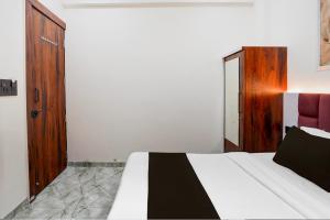 a bedroom with a white bed and a wooden door at Hotel O S.P Residency in Indore