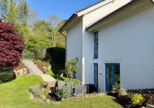 a white house with a blue door and a yard at Ferienwohnung Engels in Olpe