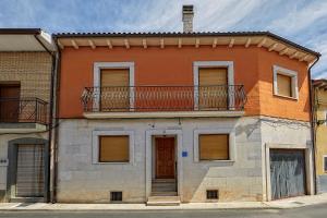 an orange building with a balcony on top of it at Casa Rural EL COTARRO DE PESQUERA DE DUERO in Pesquera de Duero