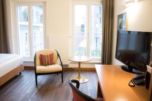 a hotel room with a bed and a tv and a chair at Hotel Leidinger - ehemalige Domicil und Domaine Leidinger in Saarbrücken