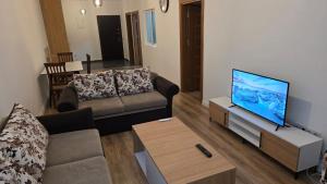 a living room with a couch and a flat screen tv at Art Apartment in Prizren