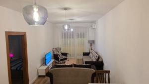 a living room with a couch and chairs and a tv at Art Apartment in Prizren