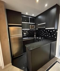 a kitchen with black cabinets and a stainless steel refrigerator at Refúgio Morumbi: Piscina aquecida e espaço gourmet in São Paulo
