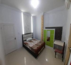 a bedroom with a bed and a door and a chair at Cozzy Aryaputra Residence in Gorontalo