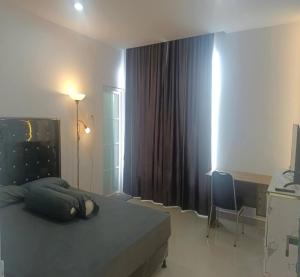 a bedroom with a bed and a desk and a window at Cozzy Aryaputra Residence in Gorontalo