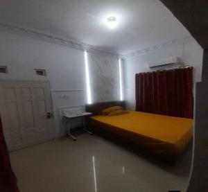 a small bedroom with a yellow bed and a door at Cozzy Aryaputra Residence in Gorontalo