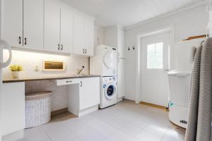 a kitchen with white cabinets and a washer and dryer at Big villa with outbuilding in Sarpsborg