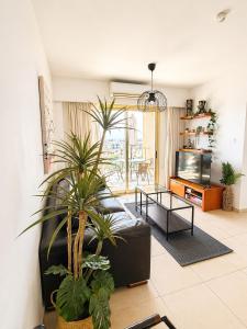 a living room with a black leather couch and plants at Stunning Sea View Resort Pools Spa Gym Balcony in Paphos