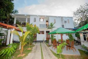a large white house with tables and chairs at Wake N Flow, Hiriketiya Beach in Hiriketiya
