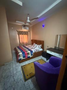 a bedroom with a bed and a purple couch at Hanover Hotels Suleja in Tunga Bai