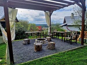 a patio with logs and a fire pit under a pergola at Chatička Lukov in Lukov