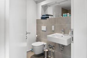 a bathroom with a white toilet and a sink at Loftbude in Hürth +17 photos