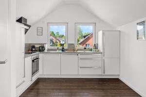 a white kitchen with white appliances and two windows at Loftbude in Hürth