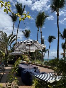 a park with a bench and an umbrella and palm trees at Pousada Morro dos Navegantes in Ilhéus