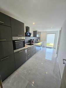 a kitchen with black cabinets and a large window at RUWERA SONNENHÜGEL - Moderne Ferienwohnung - eigener Eingang, Garten und Terrasse in Trier