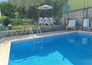 a swimming pool with a chair and an umbrella at Chalet antiguo reformado "El Mirador" in Hoyo de Pinares