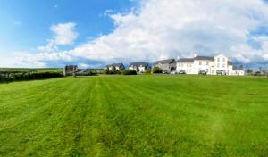 a large field of green grass with houses in the background at Aran View Loft in Knockfin Cross Roads