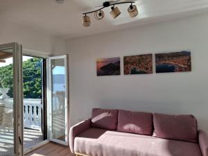 ein Wohnzimmer mit Sofa und Balkon in der Unterkunft Apartment Biondić in Starigrad
