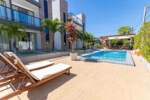 a swimming pool with a chaise lounges next to a building at Altos do Caju - Triplex in Pirangi 300 meters from the World's Largest Cashew Tree by Carpediem in Parnamirim