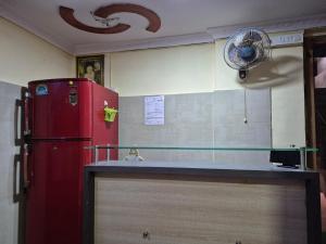 a kitchen with a red refrigerator and a fan at Swami Single Bed Dormstay in Ratnagiri