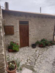 a stone house with a wooden door and potted plants at lefkara stone nest in Pano Lefkara