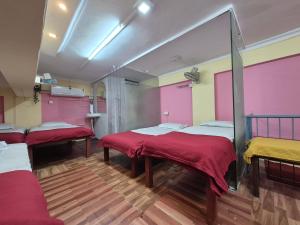 a room with three beds with red and yellow at Swami Single Bed Dormstay in Ratnagiri