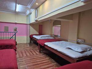 three bunk beds in a room with pink walls at Swami Single Bed Dormstay in Ratnagiri