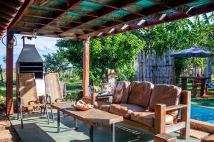 a patio with a couch and a table and an umbrella at Chalé com Piscina - Festival de Inverno de Bonito in Bonito