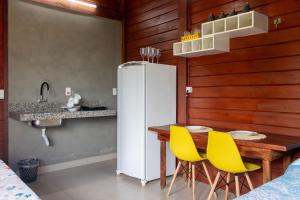 a kitchen with a table and a refrigerator and yellow chairs at Chalé com Piscina - Festival de Inverno de Bonito in Bonito