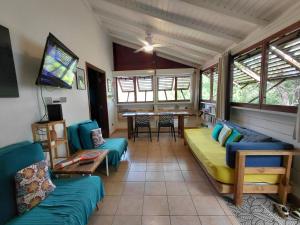 a living room with couches and a tv and a table at GîteTi Coco de Malendure - Bord de mer - 4 pers in Bouillante