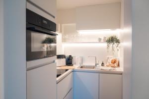 a white kitchen with a sink and a microwave at Luxurious Suite - Train Station Deinze in Deinze