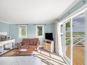 a living room with a chair and a television at Cosy Guesthouse in Tranquil Puriri, Thames in Thames