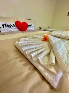 a bed with white towels and a red heart pillow at Tiny House Londres, Timbó in Timbó