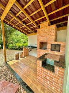 an outdoor kitchen with a brick wall and wooden floor at Tiny House Londres, Timbó in Timbó