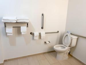 a white bathroom with a toilet and towels at Garner Hotel Pecos by IHG in Pecos