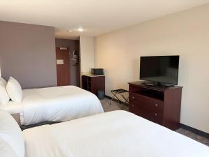 a hotel room with two beds and a flat screen tv at Garner Hotel Pecos by IHG in Pecos