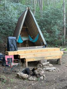 a tent with a table and a chair in the woods at The Outside Inn in Cullowhee +9 photos