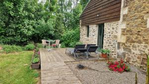a wooden deck with chairs and a table in a yard at La Maison Ronde in Saint-Quentin-sur-Charente