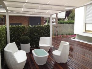 a patio with white chairs and a pergola at La Villetta in Giulianova +3 photos