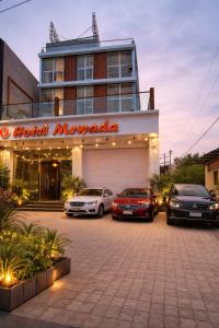 Drei Autos parkten auf einem Parkplatz vor einem Hotel. in der Unterkunft Hotel Mewada in Ujjain