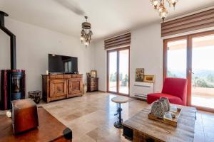 a living room with a tv and a red chair at La Dolce Rustica - Hillside Villa in Sutomore