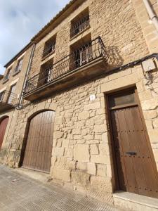 a brick building with a door and a balcony at Cozy rural apartment in Calaceite